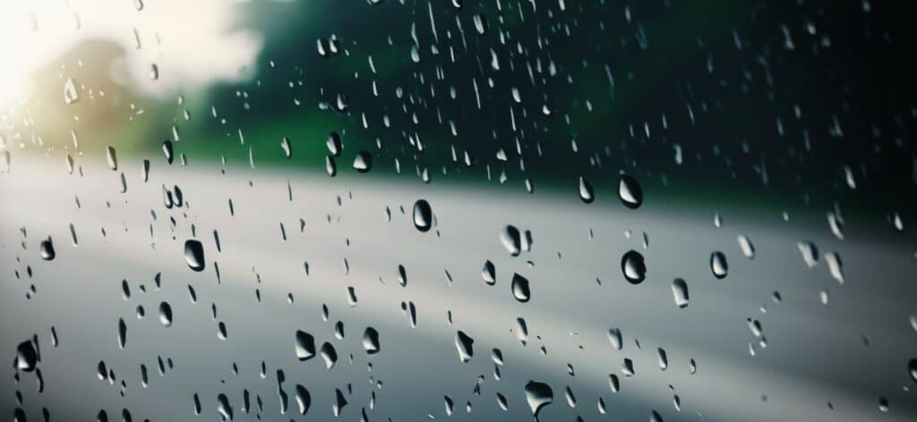 rain shower on car windshield or car window and blurry road in b