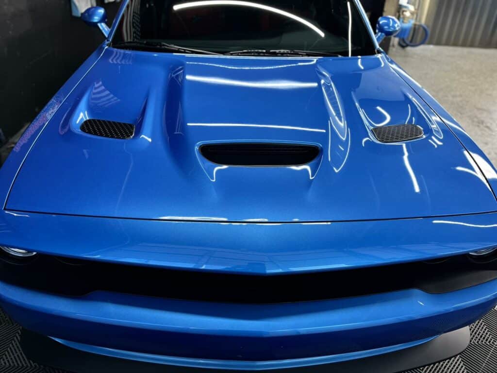 a close up of a blue sports car hood with air vents.