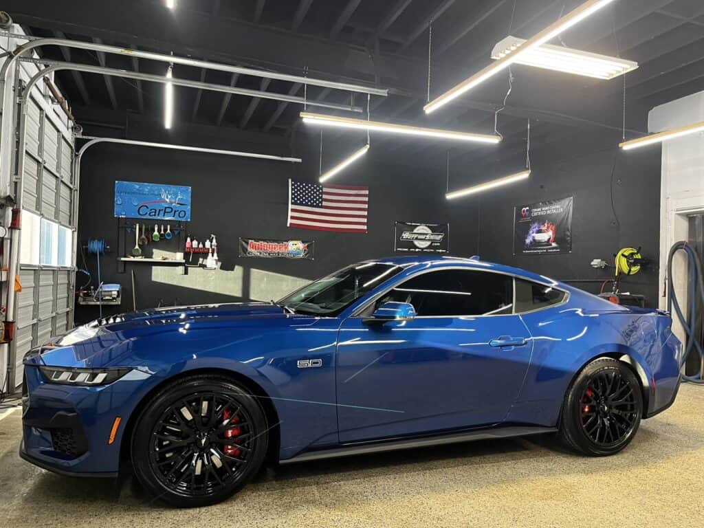 a blue sports car parked inside a well lit garage with automotive themed decor.