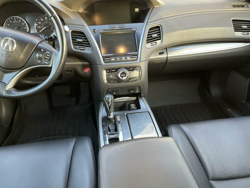 interior view of a vehicle showcasing the steering wheel, dashboard, center console, and leather seats.