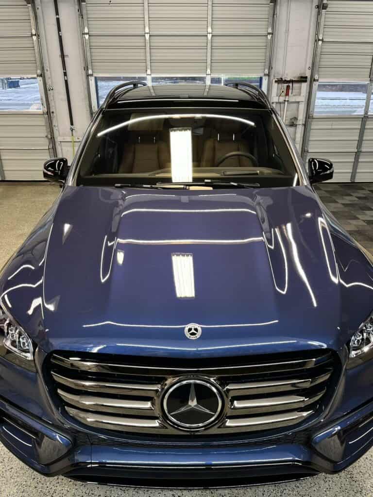 a blue mercedes benz vehicle parked indoors, seen from the front perspective.